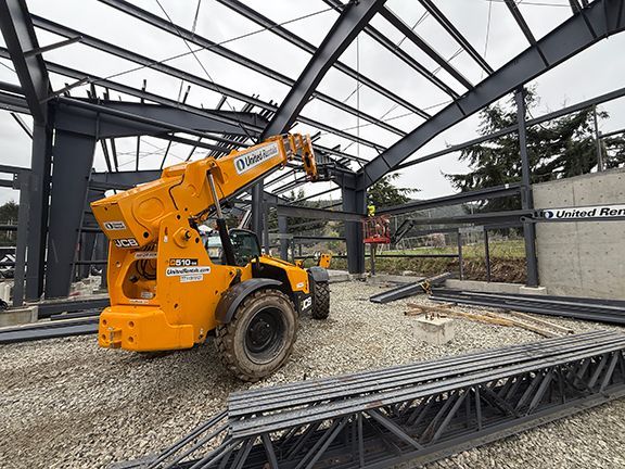 Crane elevates steel components to be added to metal building roofing beams.