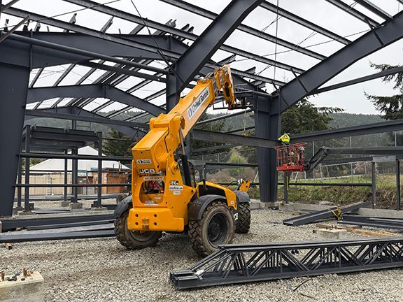 Construction team lifts metal components with crane on construction site.