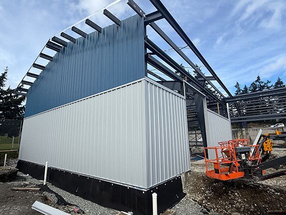 Side view of the grey and blue metal wall panels at commercial building construction.