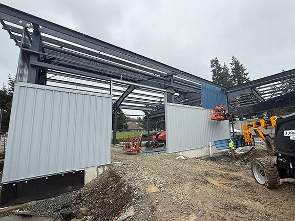 Skilled trades team adds blue metal siding to upper level of commercial building.