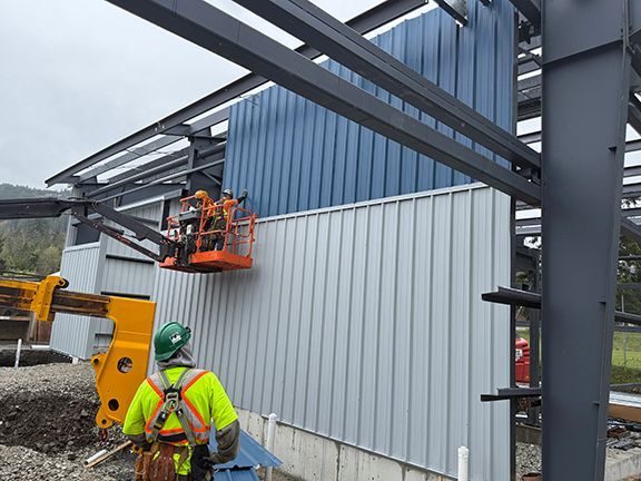 Construction team adding metal wall panels on industrial building construction site in BC.