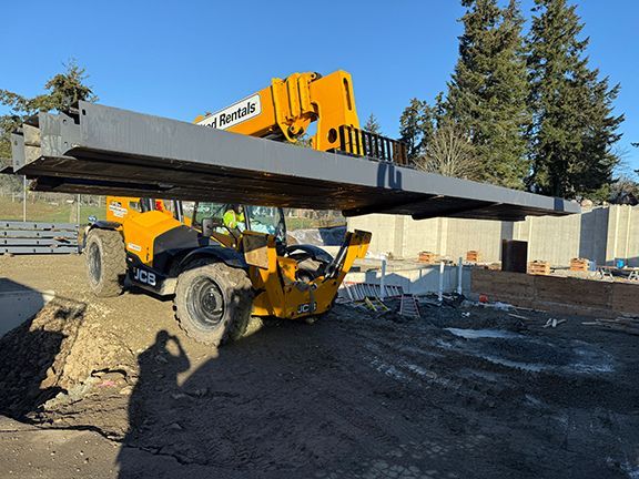 Pre-engineered steel beams are carried into place for industrial metal building project in BC.