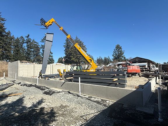 Steel beam being lifted into place on concrete foundation in British Columbia.