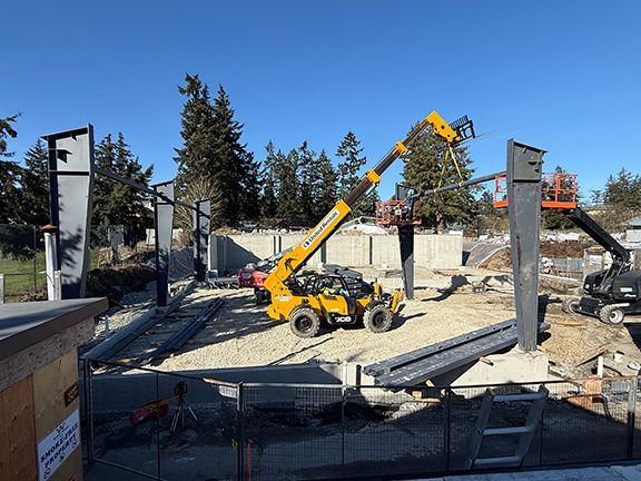 Four corner structural steel beams fitted into place at industrial construction site.