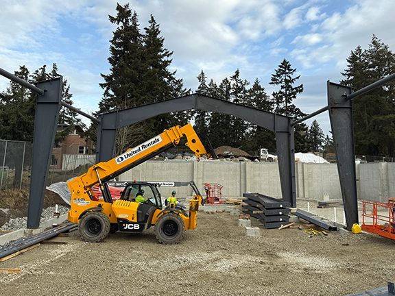 Yellow crane working at metal building construction site in British Columbia.