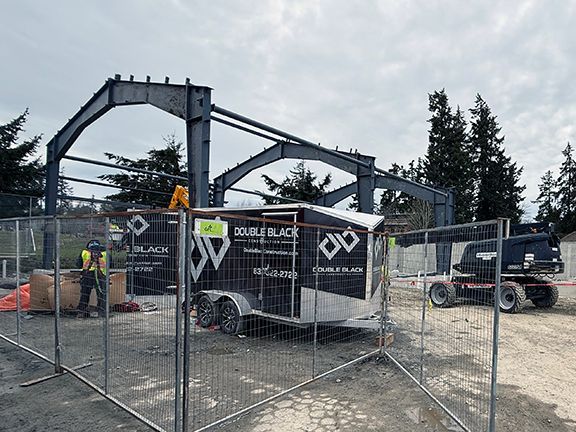 Skilled tradesperson stands in front of steel framing at industrial building construction site.