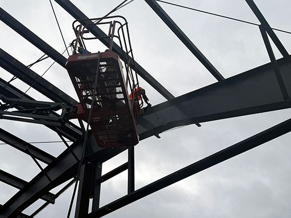 Skilled tradesperson spraying water to clean steel building frames.