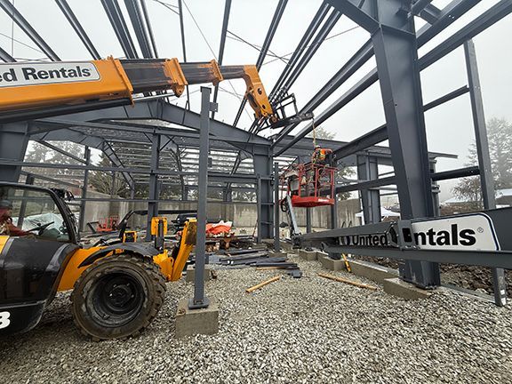 Skilled trades crew cleaning the steel frames of an industrial building under construction.