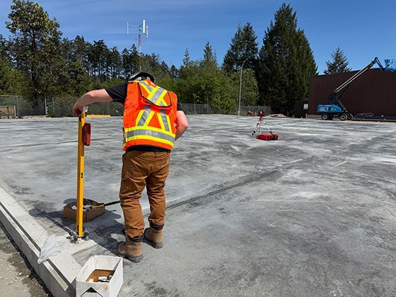 Tradesperson inspects concrete foundation pad in Nanaimo, BC.