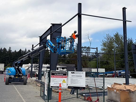 Skilled team of workers add steel I-beams to building construction project.