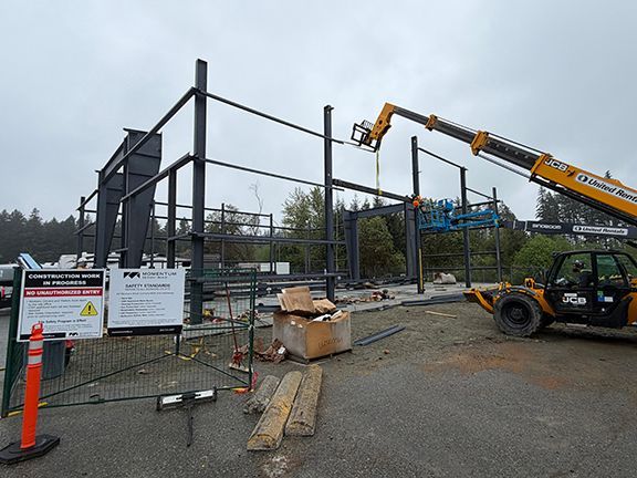 Construction team uses crane to add more steel beams to building job