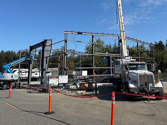 Crane elevator lower steel beams into place for building project.