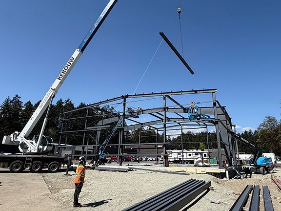 Steel beam gets lowered into place for roof structure at metal building project.