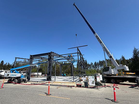 Crane lowers I-beam into place at PEMB site.