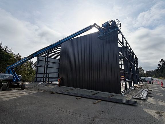 Metal side wall panels being added to PEMB structure.