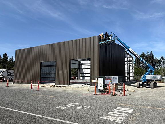 Construction crew adds metal wall panels to building.