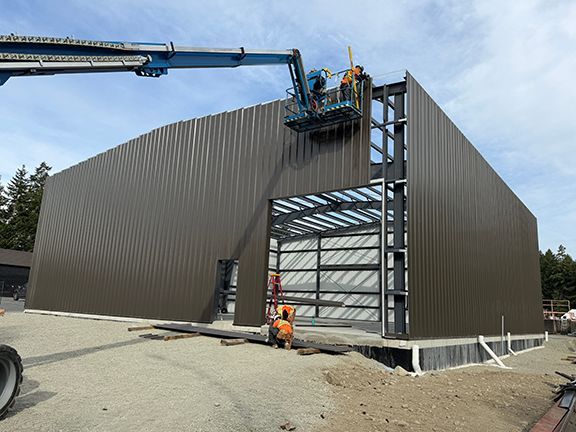 Team uses elevator to add metal panels to top of PEMB structure.