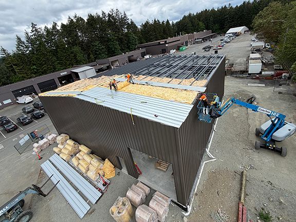 Construction team adds metal roofing panels to PEMB structure