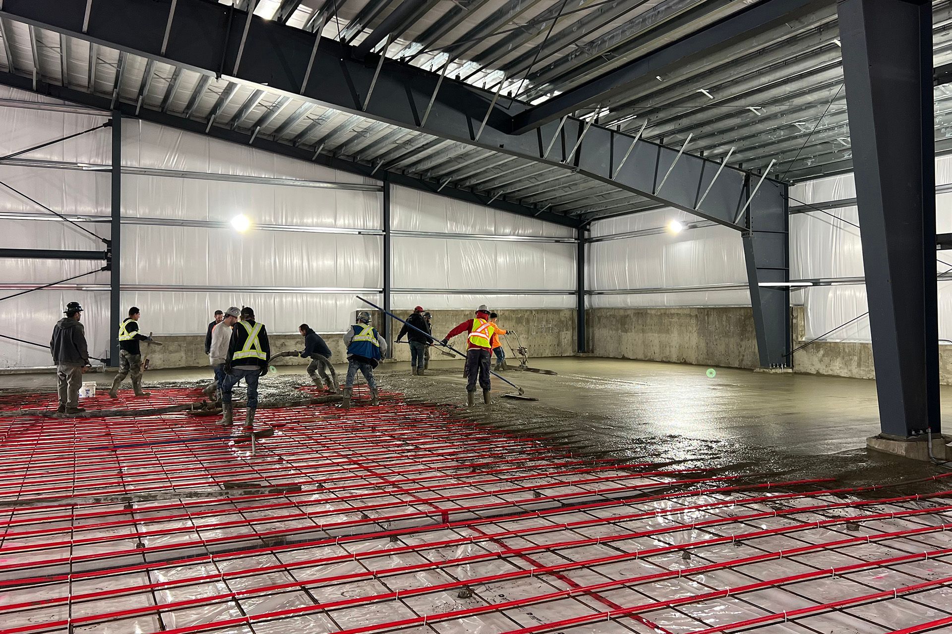 A group of construction workers are working on the floor of a building.