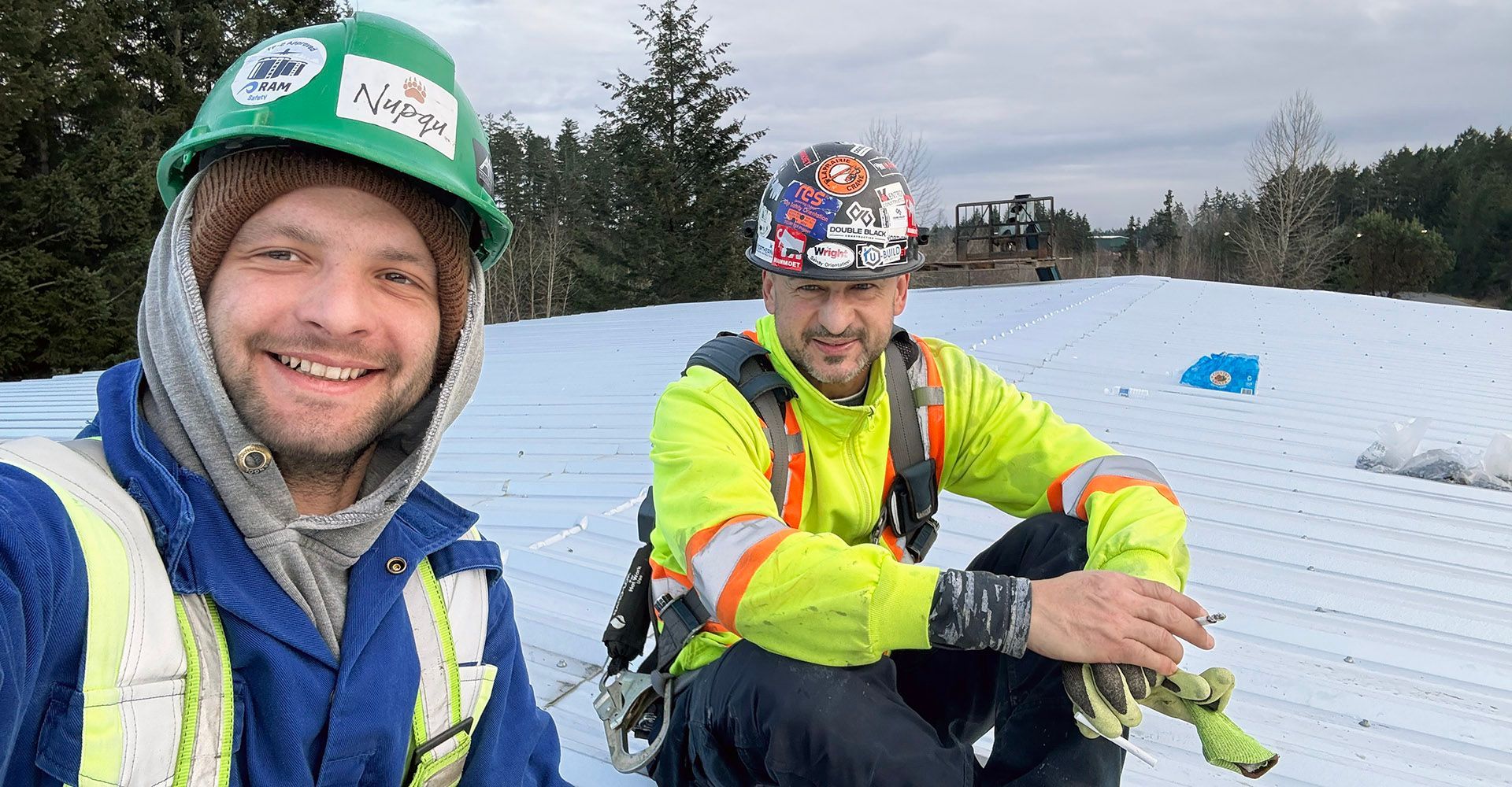 Tradesperson Cyril and John Lohan atop a metal building project in British Columbia.
