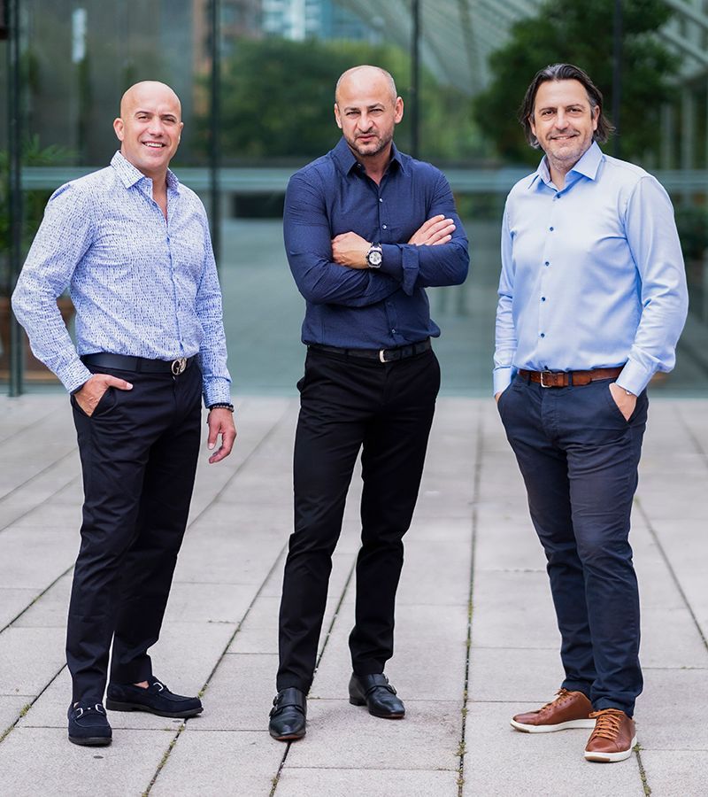 Three men standing next to each other with their arms crossed