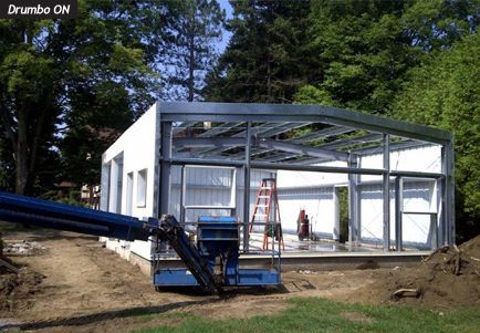 A blue crane is sitting in front of a building under construction.