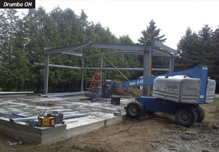 A blue genie lift is parked in front of a building under construction