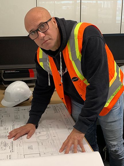Frank Melo with blueprint plans for a commercial metal building.