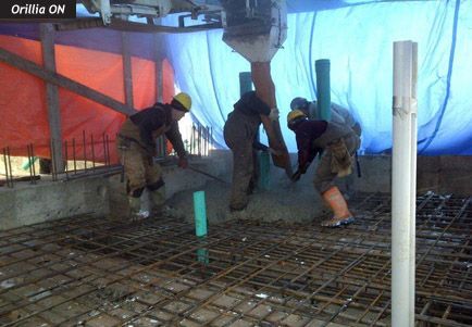 A group of construction workers are working on a concrete floor