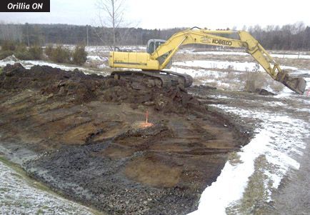 A kobelco excavator is digging a hole in the dirt