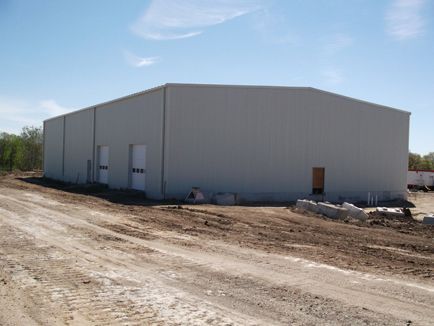 A large white building is being built in the middle of a dirt road.