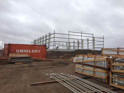 A large red uniglory shipping container is sitting in a construction site.