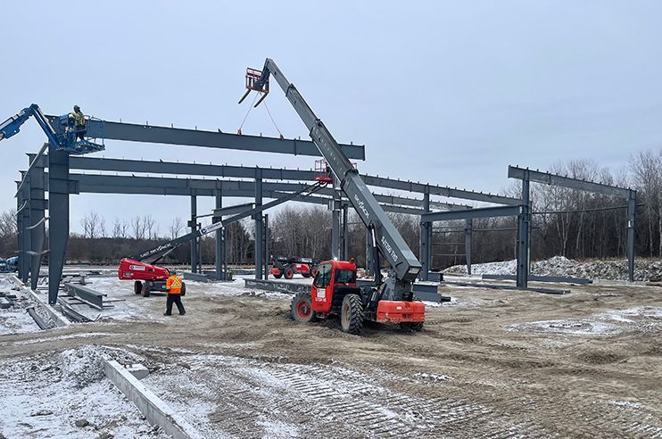 A large metal structure is being built in the snow.
