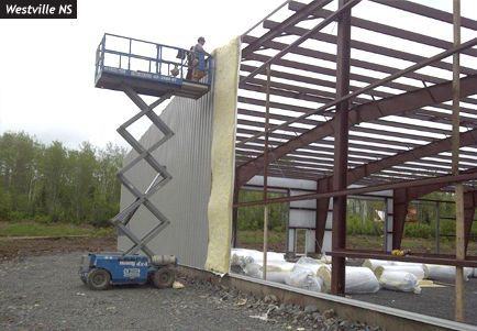 A man on a scissor lift is insulating a building in westville ns