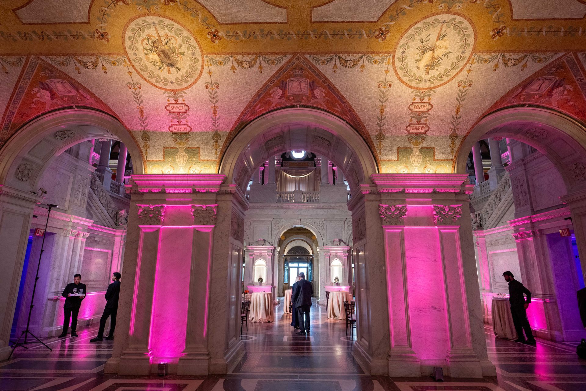 A large room with pink lights on the walls and columns.
