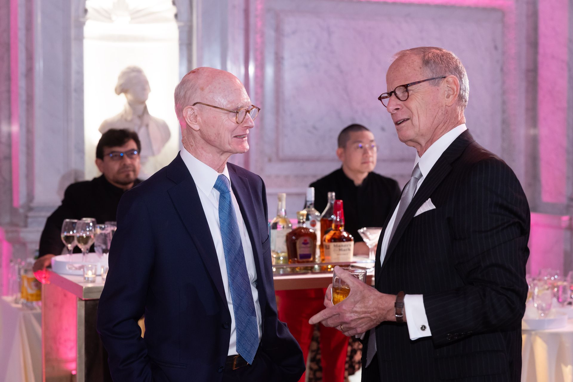 Two men in suits and ties are talking to each other in a room.