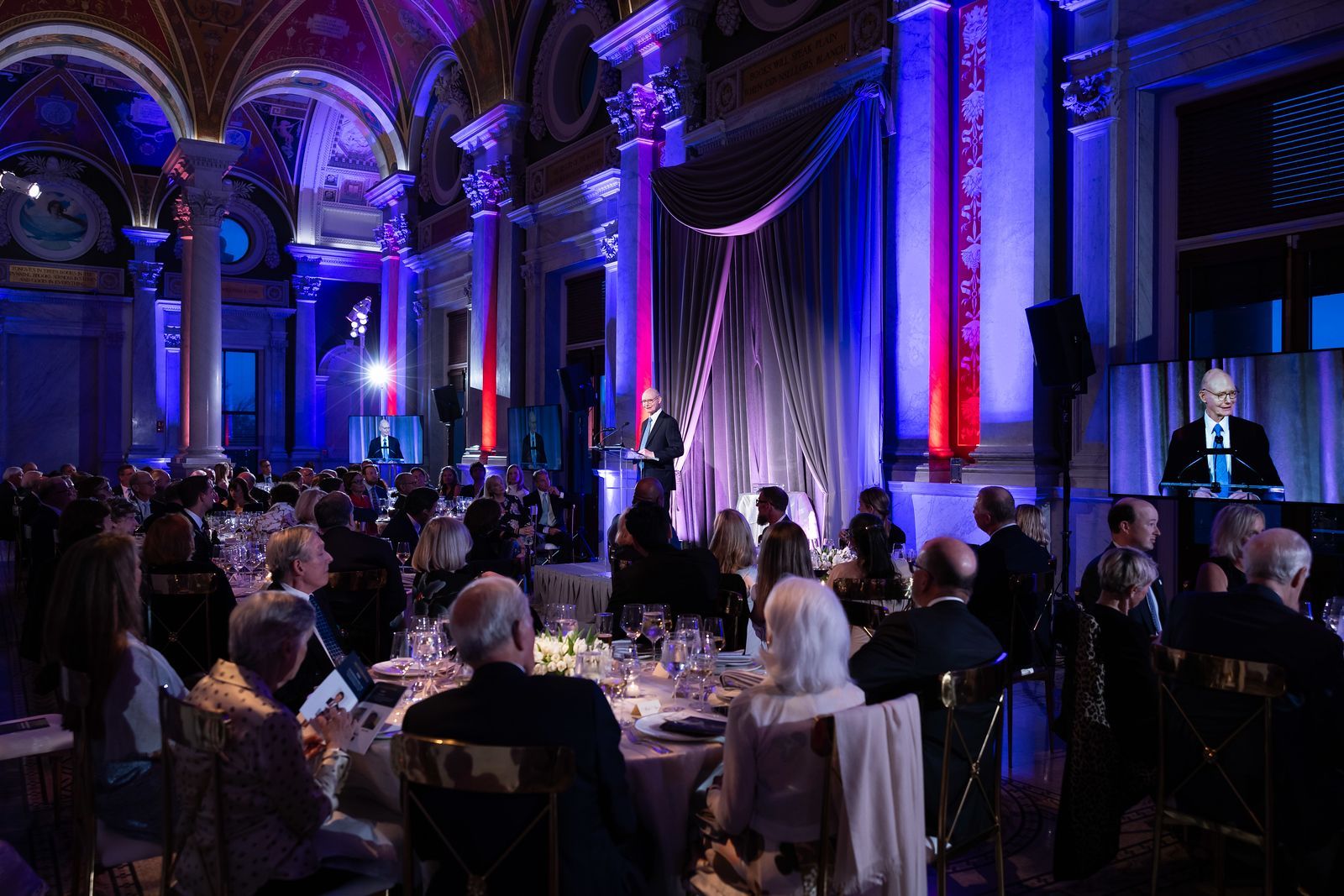 A group of people are sitting at tables in a large room.