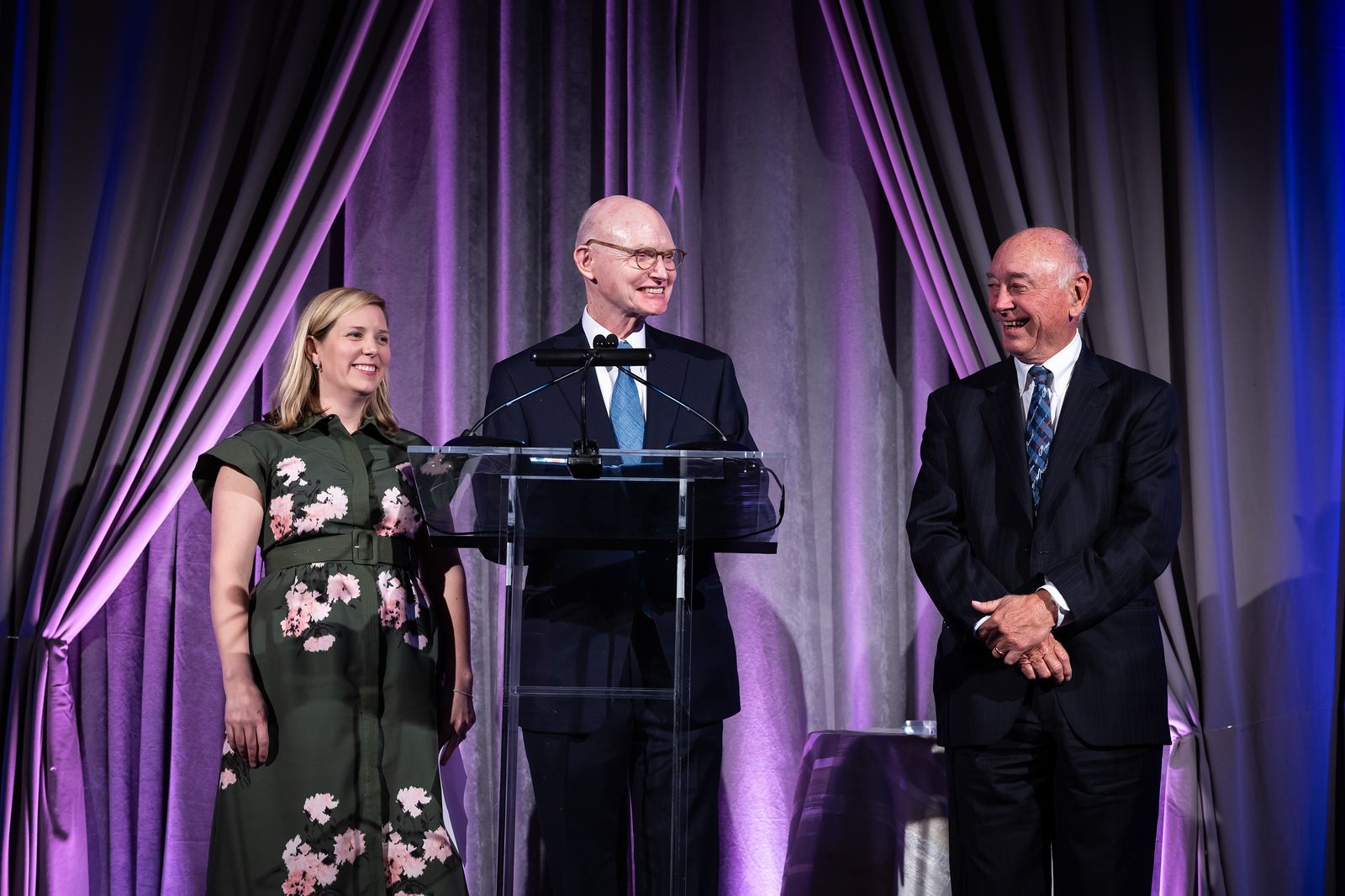 Three people are standing in front of a podium.