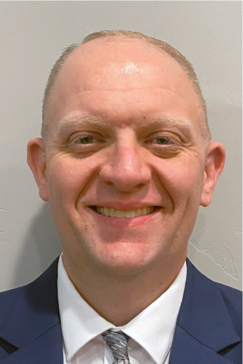 A man in a suit and tie is smiling for the camera.