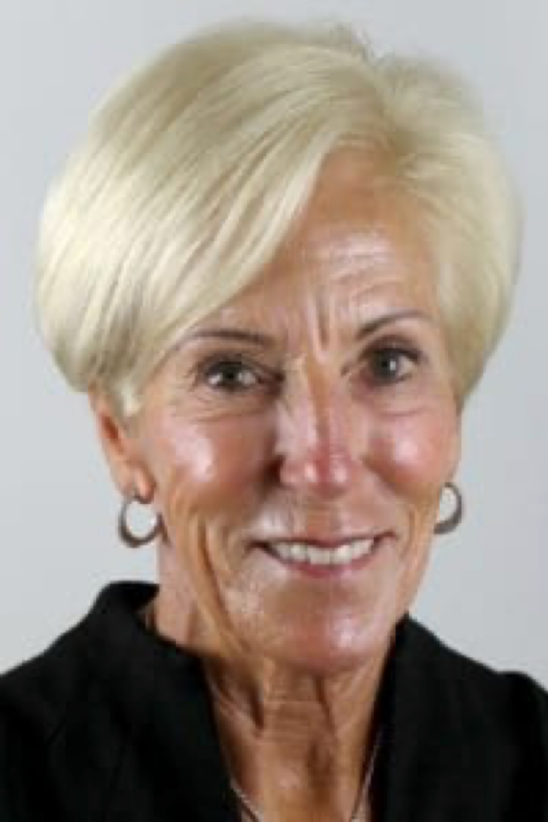 A woman with blonde hair and earrings is smiling for the camera.