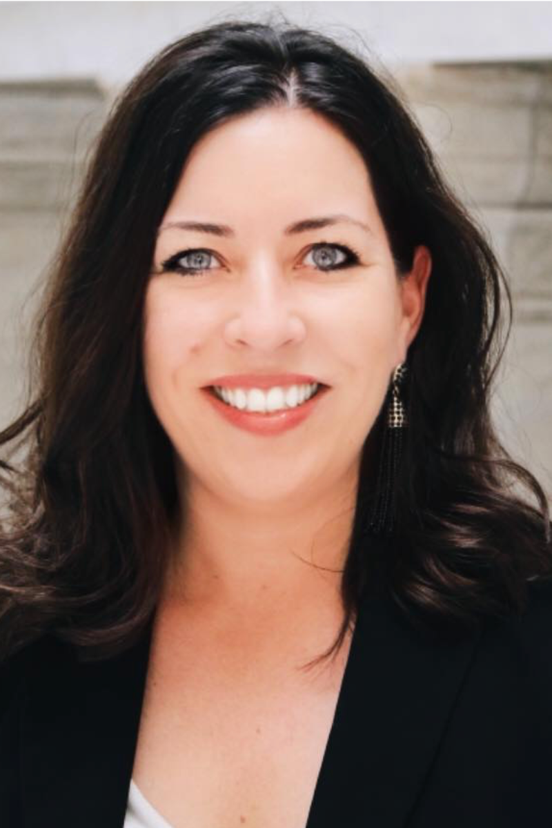 A woman with long dark hair is smiling for the camera
