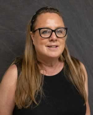 A woman wearing glasses and a black tank top is smiling for the camera.