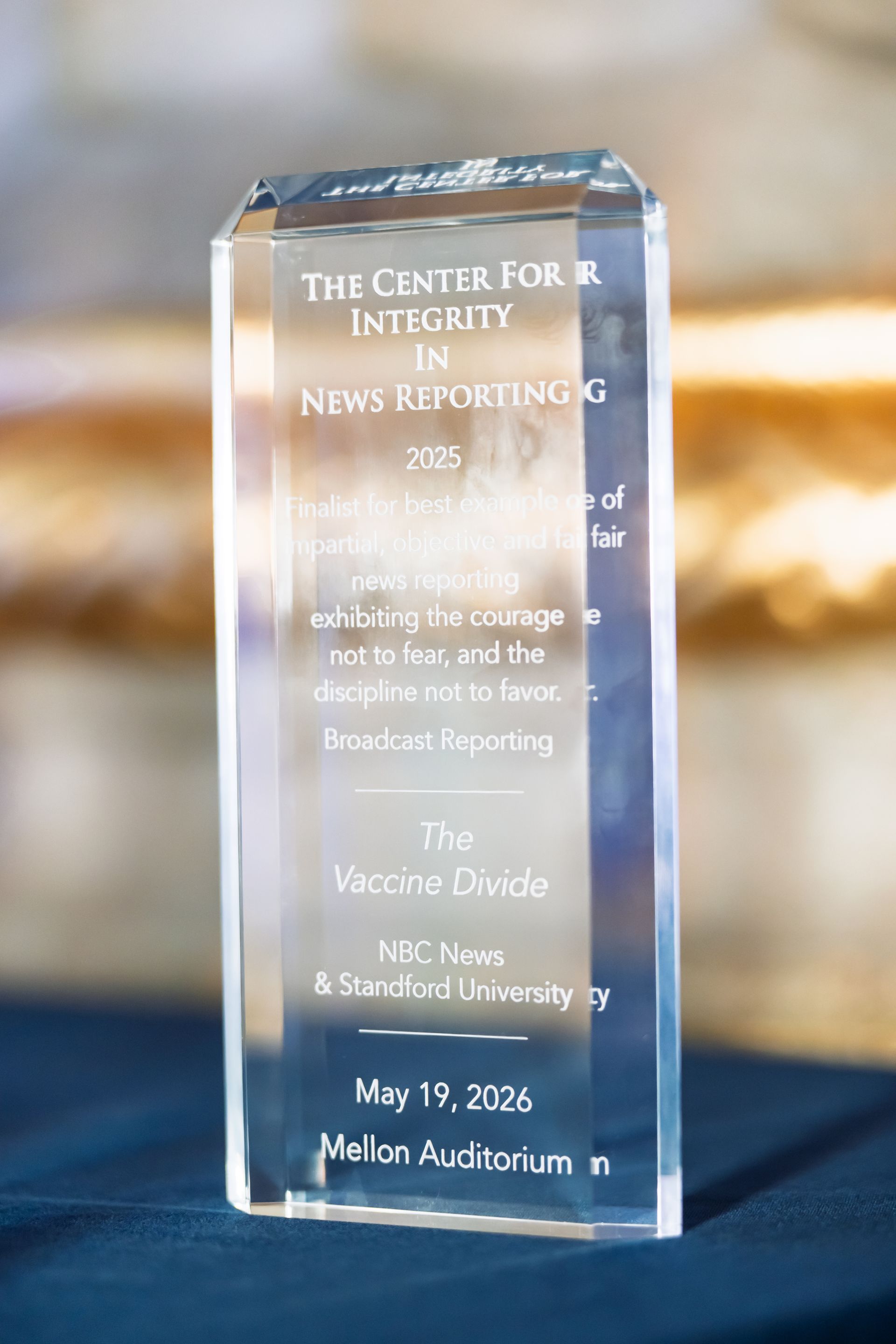 Clear glass award on a table, engraved with “The Center for Integrity in News Reporting” and event details
