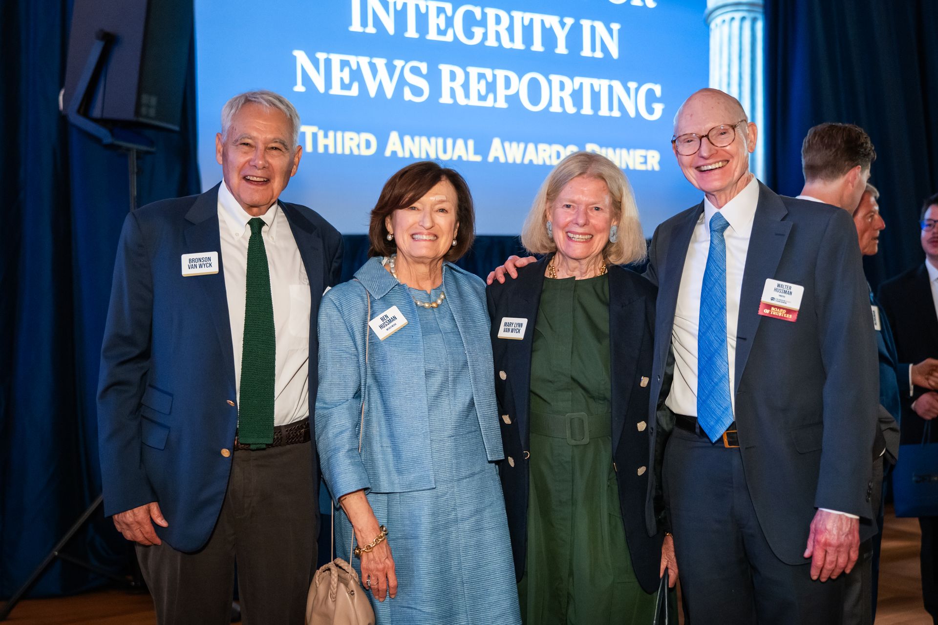 Four people posing at an Integrity in News Reporting award event in front of a blue backdrop