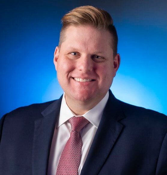A man in a suit and tie is smiling for the camera