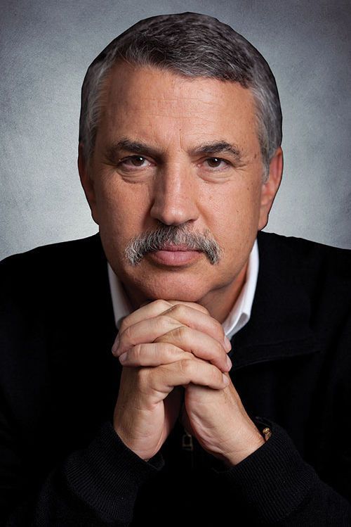 Studio portrait of a man with gray hair and mustache, resting clasped hands under his chin on a gray background
