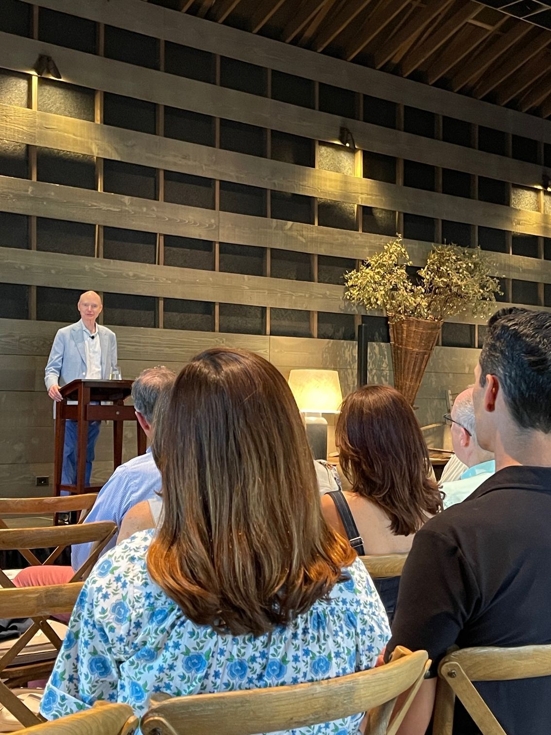 A man is standing at a podium giving a speech to a group of people sitting in chairs.