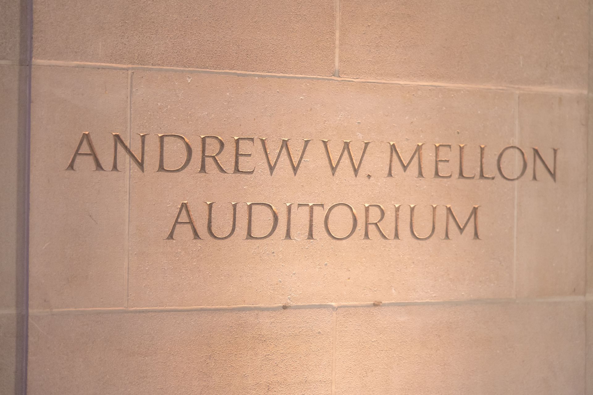 Stone wall plaque reading “Andrew W. Mellon Auditorium”