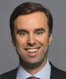 A man in a suit and tie is smiling for the camera