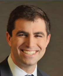 A man in a suit and tie is smiling for the camera